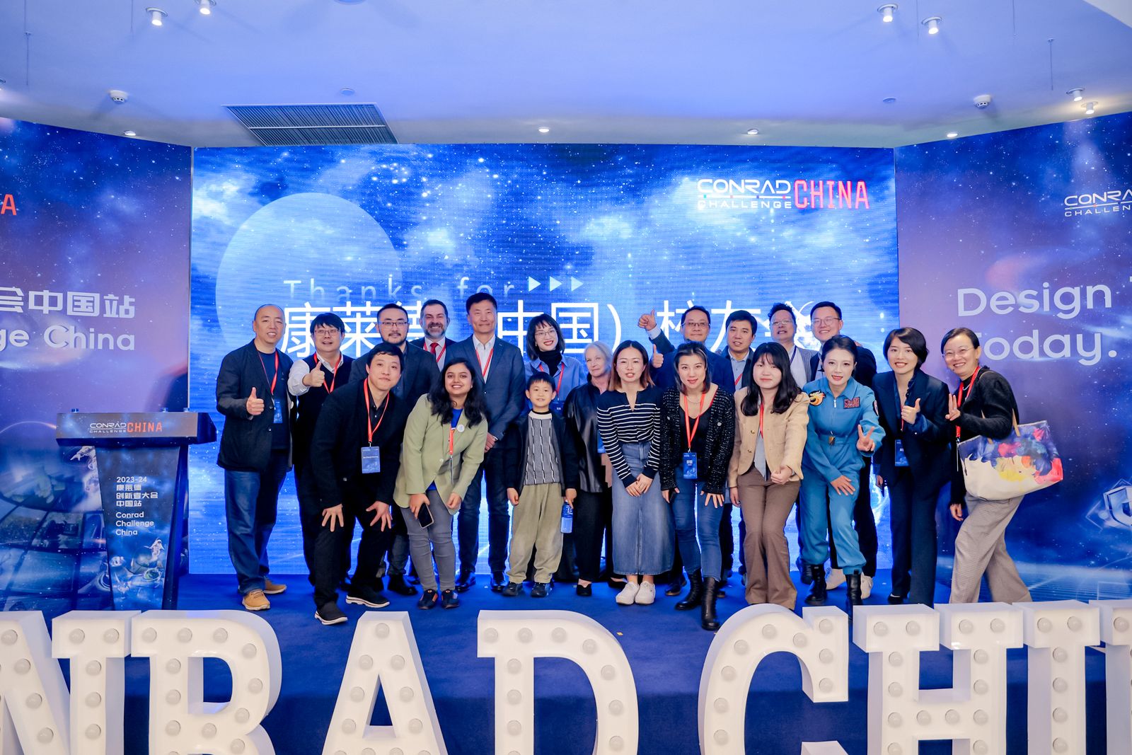A large group of people poses together on a stage at a 